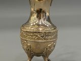 an image of a silver vase on a stand on a gray surface