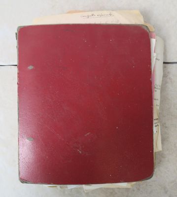 un livre rouge posé sur un sol carrelé blanc