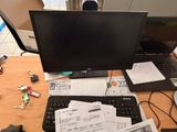 a desk with a laptop, monitor, keyboard, and papers on it