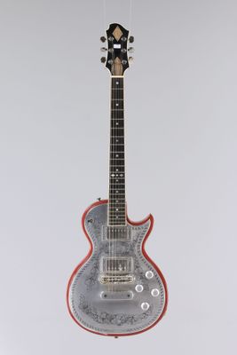 une guitare électrique suspendue à une ficelle sur un mur blanc