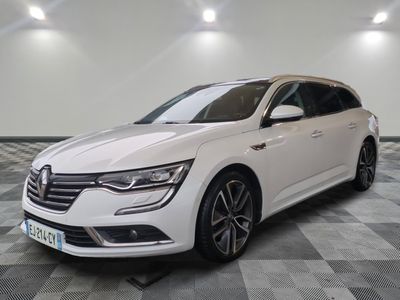 a white car is parked on a checkered floor in a garage