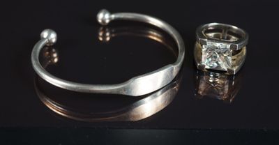 un bracelet en argent et une bague en diamant posés sur un fond noir