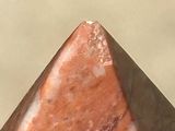 a close up of a red stone pyramid on a table
