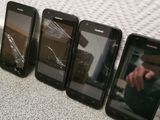 four cell phones are sitting next to each other on a table