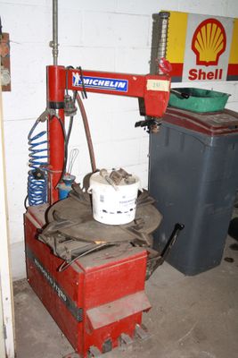 a red machine with a bucket on it in a garage