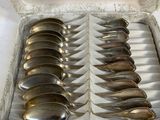 silver spoons in a box on a table with a white background