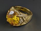 an image of a gold ring with a yellow stone surrounded by white diamonds