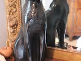 a statue of a cat sitting on a table next to a mirror