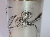 a silver cup with a design on it on a white surface