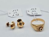 deux bagues en or et une paire de boucles d'oreilles posées sur une surface blanche