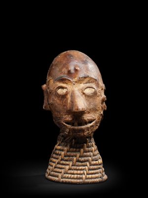 une tête sculptée représentant un homme barbu portant un col