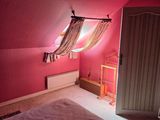 a bedroom with a pink wall and a bed with a white comforter