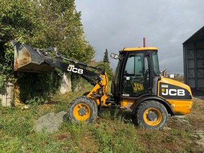a backhoe of a construction vehicle that is parked in the grass