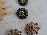 five different colored brooches on a white surface