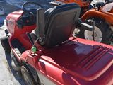 a red lawn mower parked next to a red tractor