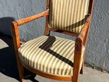 une vieille chaise en bois dont l'assise est recouverte d'un tissu rayé