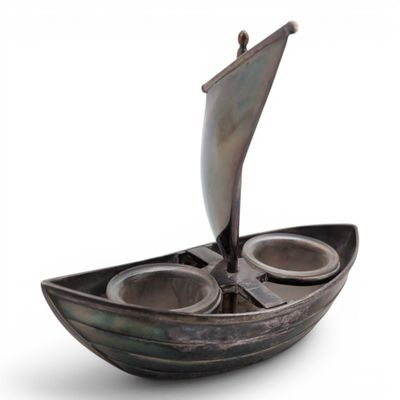 a small boat with two cups in it on a white surface