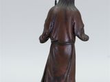 a bronze statue of a man standing on a base with his hands in his pockets