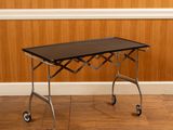 une photo d'une table noire à roulettes posée sur un parquet
