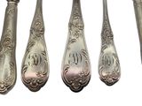 six spoons and a fork are lined up on a white surface