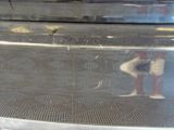 a reflection of a man standing on the side of an oven