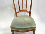 an old wooden chair with green upholstered seat on a white background
