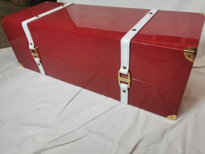 une boîte rouge bordée de blanc, posée sur un lit