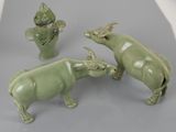 trois figurines d'animaux en céramique verte et un vase posés sur une table