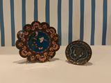 two decorative plates sitting on a table with blue and white striped wallpaper