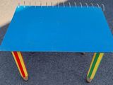 une petite table bleue avec des pieds de différentes couleurs