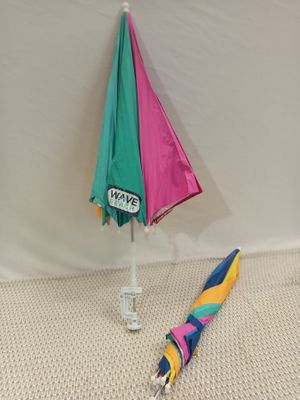 a colorful umbrella that is on the ground next to a sign