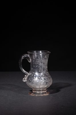 an old glass pitcher sitting on top of a black table