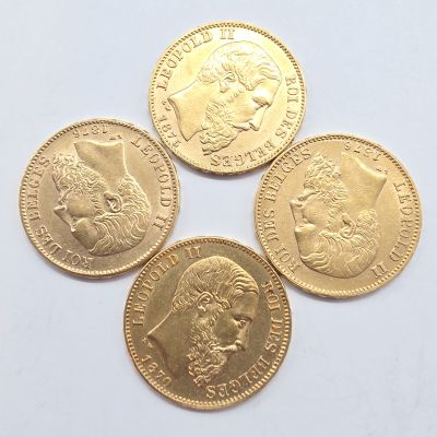 quatre types différents de pièces d'or reposant sur une surface blanche