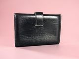 a black leather wallet on a pink background