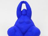 a close up of a blue sculpture of a person sitting on a white surface