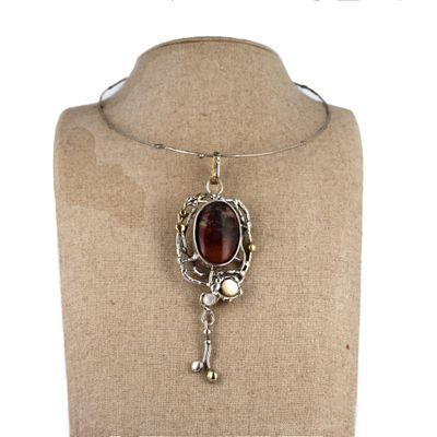 collier en argent orné d'une pierre rouge et d'une clé, porté par un mannequin