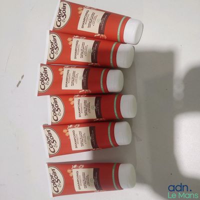 Plusieurs tubes de dentifrice sont alignés sur une surface blanche