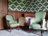 deux chaises vertes dans une pièce dont l'un des murs est tapissé