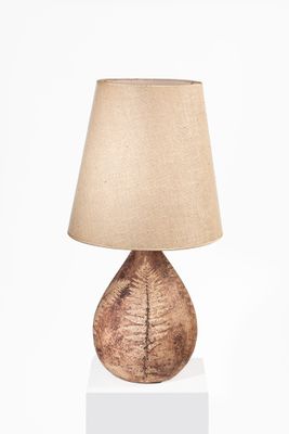 un gros plan d'une lampe posée sur un socle blanc, avec un abat-jour marron