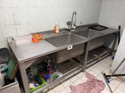 a sink in the corner of a kitchen with a lot of cleaning supplies