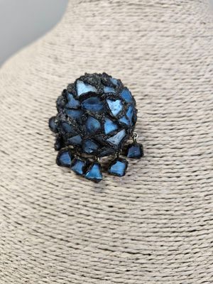 a close up of a blue flower broochle on a mannequin