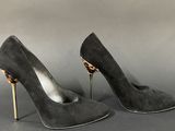 black sued stil heels with gold heelings on a grey background