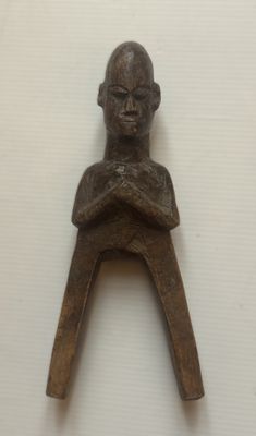 une petite sculpture en bois représentant un homme assis sur une chaise