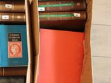 many books in a box on the floor next to each other