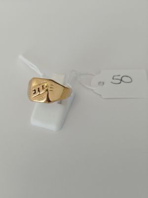a close up of a gold ring on a white surface with a price tag