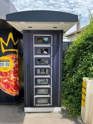 un distributeur automatique sur le côté duquel est posée une pizza