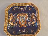 une assiette bleue et dorée sur laquelle est représentée une femme