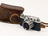 un étui en cuir marron auquel est attaché un appareil photo