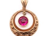 un gros plan d'un pendentif en or orné d'une pierre rose