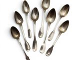 six silver spoons are arranged in a circle on a white surface